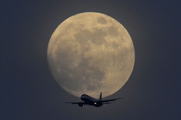 Самолет на фоне полной луны в небе над Лондоном, Великобритания - Sputnik Абхазия