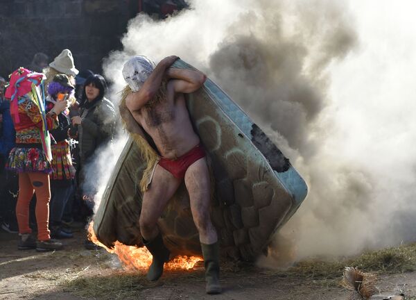Участник в маске несет горящий матрас во время ежегодного карнавала, проходящего со стародавних времен, в деревне Зубьета на севере Испании - Sputnik Абхазия