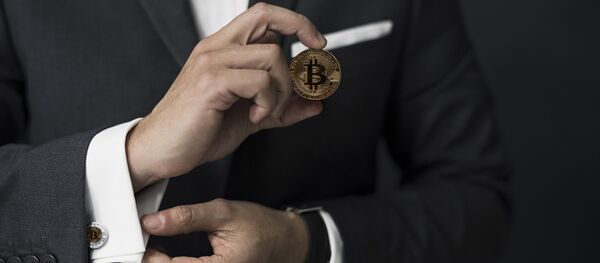 Бизнесмен держит в руках монету биткойн - Sputnik Абхазия