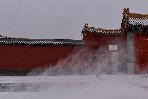 Китайский турист стоит у Императорского дворца во время снегопада в Шэньяне - Sputnik Абхазия