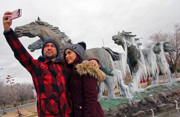 Пара делает селфи перед памятником, покрытым льдом, после похолодания в Сьюдад-Хуаресе, Мексика - Sputnik Абхазия