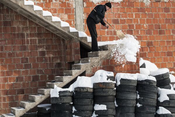 Мужчина убирает снег с лестницы дома в деревне Мрамор, Приштина, Сербия - Sputnik Абхазия
