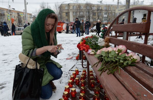 Женщина зажигает свечу возле здания торгового центра «Зимняя вишня» в Кемерово, где произошел пожар - Sputnik Абхазия