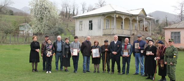 Родственники участника ВОВ Наиба Ахба, данные о котором переданы семье в рамках проекта Возвращение имени стоят на фоне родового дома в селе Ачандара Родственники участника ВОВ Наиба Ахба, данные о котором переданы семье в рамках проекта Возвращение имени стоят на фоне родового дома в селе Ачандара - Sputnik Абхазия