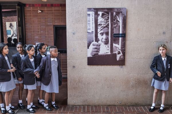 Южноафриканские школьницы рядом с плакатом, изображающим экс-жену Нельсона Манделы Винни на стене ее дома в Соуэто - Sputnik Абхазия