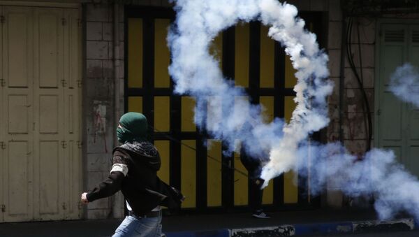 Палестинский демонстрант бросает газовую шашку в израильских солдат во время столкновений на Западном берегу реки Иордан - Sputnik Аҧсны