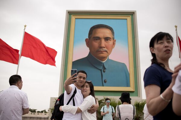 Пара делает селфи на фоне портрета китайского революционера Сунь Ятсена во время празднования 1 мая в Пекине - Sputnik Абхазия