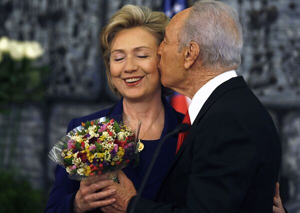 Президент Израиля Шимон Перес целует госсекретаря США Хиллари Клинтон, преподнося ей букет в конце совместной пресс-конференции после их встречи в Иерусалиме, 2009 год - Sputnik Абхазия