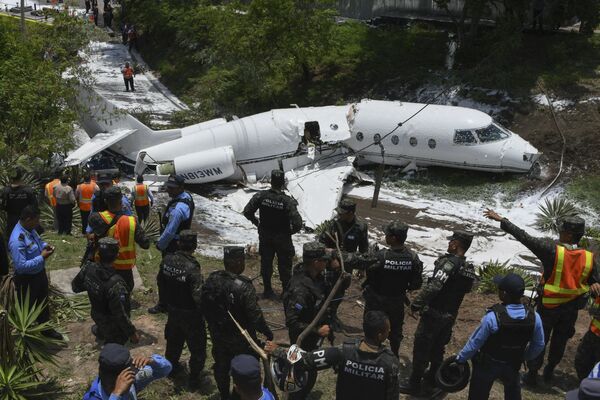 Полиция и спасатели работают у самолета, выкатившийся за пределы взлетно-посадочной полосы и развалившегося на части после приземления в международном аэропорту Тонконтин в Тегусигальпе, Гондурас - Sputnik Абхазия