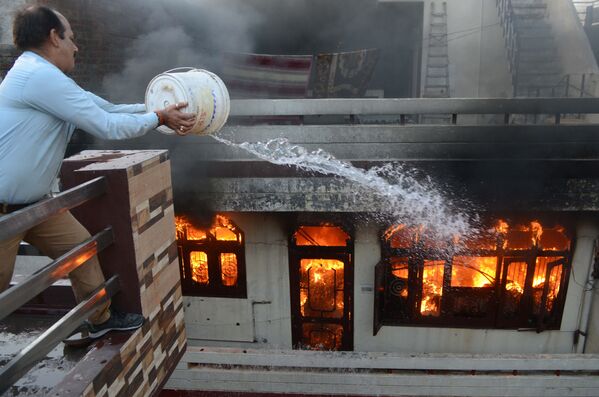 Мужчина пытается потушить пожар в магазине электротоваров в городе Амритсар, Индия. - Sputnik Абхазия
