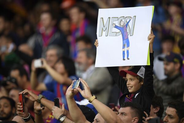 Юный болельщик с плакатом с изображнием форварда Барселоны Лионеля Месси перед матчем между Барселоной и Реал Мадридом в Барселоне - Sputnik Абхазия