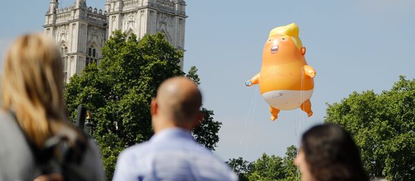 Люди проходят мимо воздушного шара с изображением президента США Дональда Трампа Люди проходят мимо воздушного шара с изображением президента США Дональда Трампа - Sputnik Абхазия