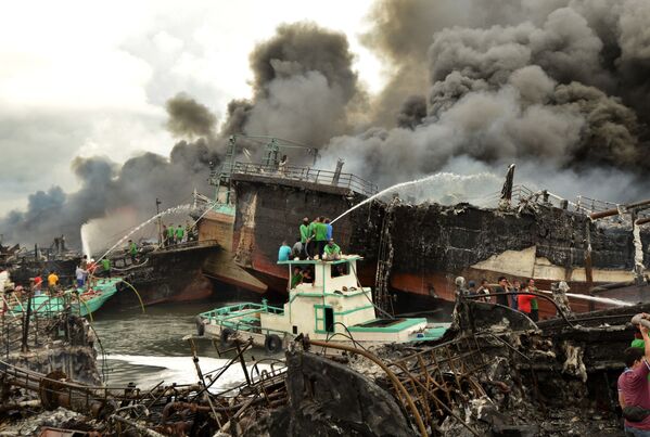 Рабочие и пожарные тушат рыбацкие лодки в Денпасаре - Sputnik Абхазия