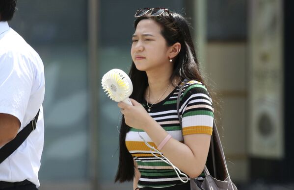Девушка с карманным вентилятором на улице Токио во время аномальной жары - Sputnik Абхазия