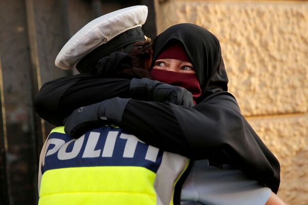Испуганная женщина обнимает полицейского во время демонстрации за запрет на ношение хиджабов в Копенгагене, Дания - Sputnik Абхазия