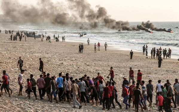 Палестинцы уносят раненого во время столкновений с военнослужащими Израиля на пляже в Газе - Sputnik Абхазия