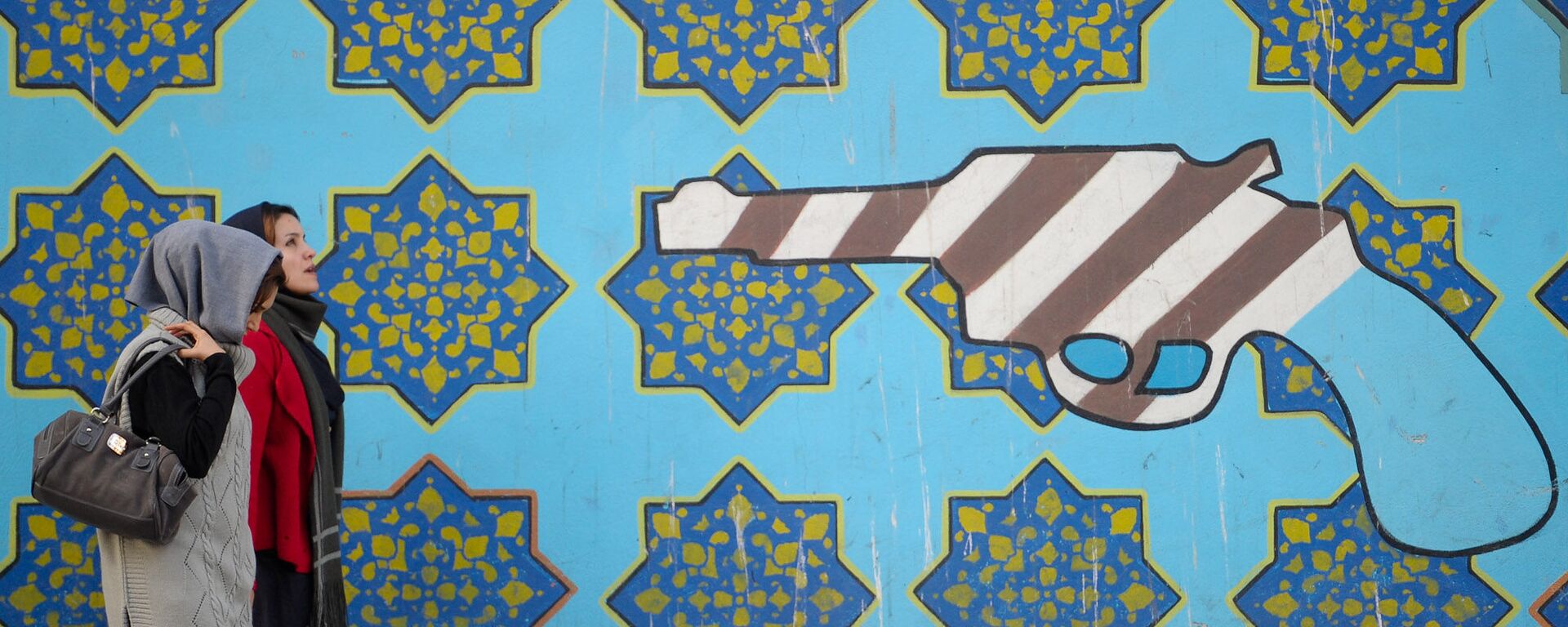 Женщины идут вдоль стены здания бывшего посольства США в Тегеране - Sputnik Абхазия, 1920, 13.03.2026