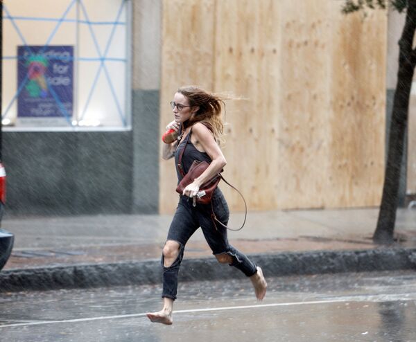 Девушка бежит босиком во время урагана Флоренс в Уилмингтоне, США - Sputnik Абхазия