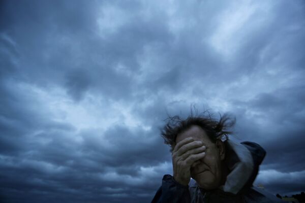 Мужчина закрывает лицо от ветра и песка во время урагана Флоренс на Мертл-Бич, США - Sputnik Абхазия