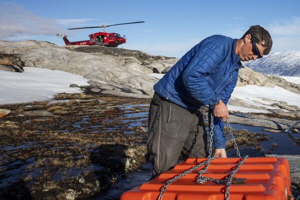 Сотрудник службы безопасности собирает оборудование для работы в научном лагере на леднике Хелхейм в Гренландии - Sputnik Абхазия