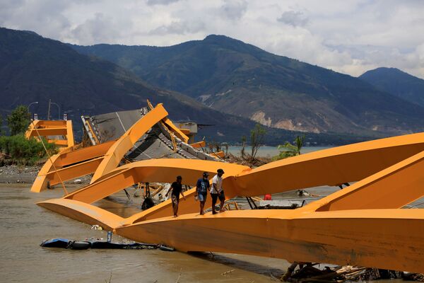 Люди идут по сломанному в результате землетрясения мосту в Палу на острове Сулавеси, Индонезия - Sputnik Абхазия