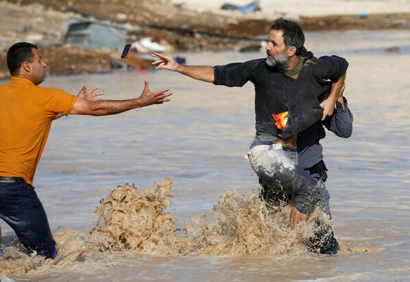 Палестинец кидает мобильный телефон товарищу во время своего задержания израильским полицейским в готовящемся к сносу бедуинском поселении Khan al-Ahmar на Западном берегу реки Иордан - Sputnik Абхазия