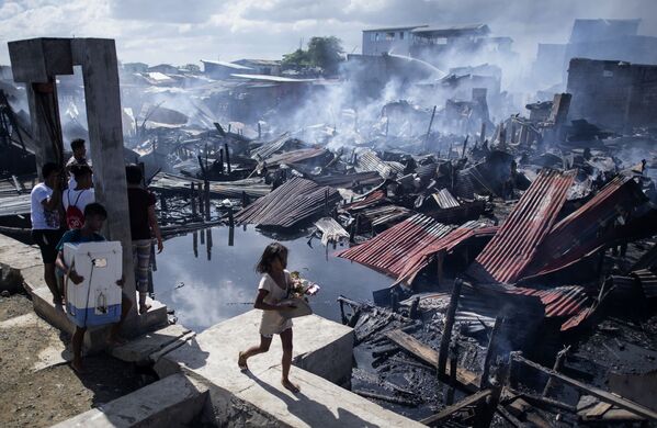 Девочка проходит мимо разрушенных домов после пожара, охватившего район трущоб в Навотасе, Филиппины - Sputnik Абхазия