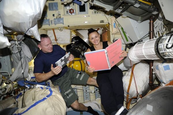 Российский космонавт Елена Серова во время чтения книги действий в чрезвычайных ситуациях EMER-1a на борту МКС - Sputnik Абхазия