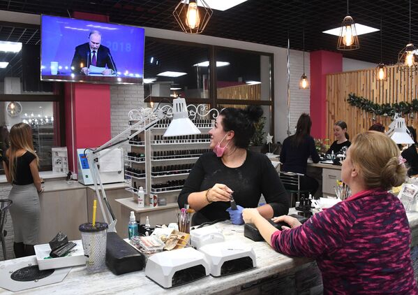 Женщины смотрят прямую трансляцию ежегодной большой пресс-конференции президента РФ Владимира Путина в салоне красоты во Владивостоке - Sputnik Абхазия
