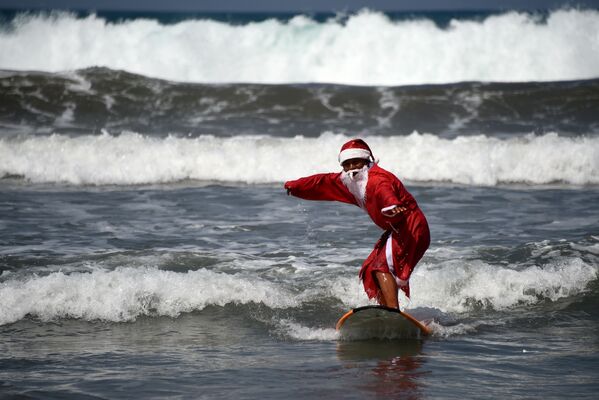 Мужчина в костюме Санта-Клауса во время серфинга на острове Бали  - Sputnik Абхазия