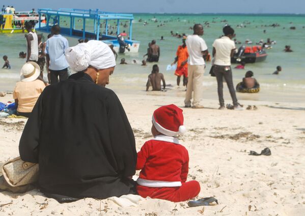 Мальчик в костюме Санта-Клауса рядом с матерью на пляже в Кении  - Sputnik Абхазия