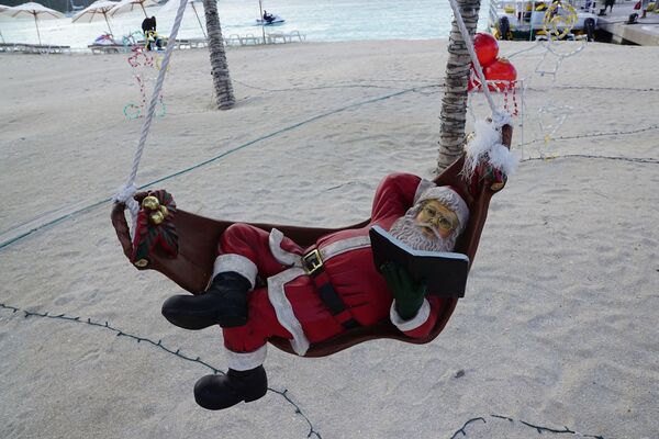 Санта-Клаус во время чтения книги на пляже острова Сен-Мартен - Sputnik Абхазия