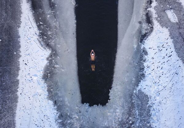 Человек плавает в частично замерзшем озере в Шэньяне, провинция Ляонин - Sputnik Абхазия