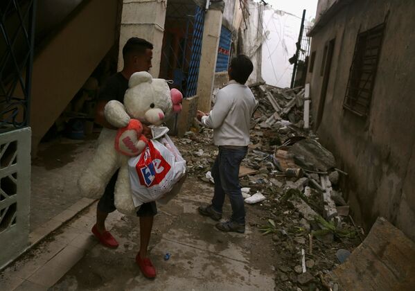 Мужчина с личными вещами среди разрушений  в результате прохождения торнадо в Гаване - Sputnik Абхазия