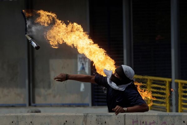 Демонстрант кидает бутылку с зажигательной смесью во время протестов против президента Гондураса Хуана Орландо Эрнандеса в Тегусигальпе - Sputnik Абхазия
