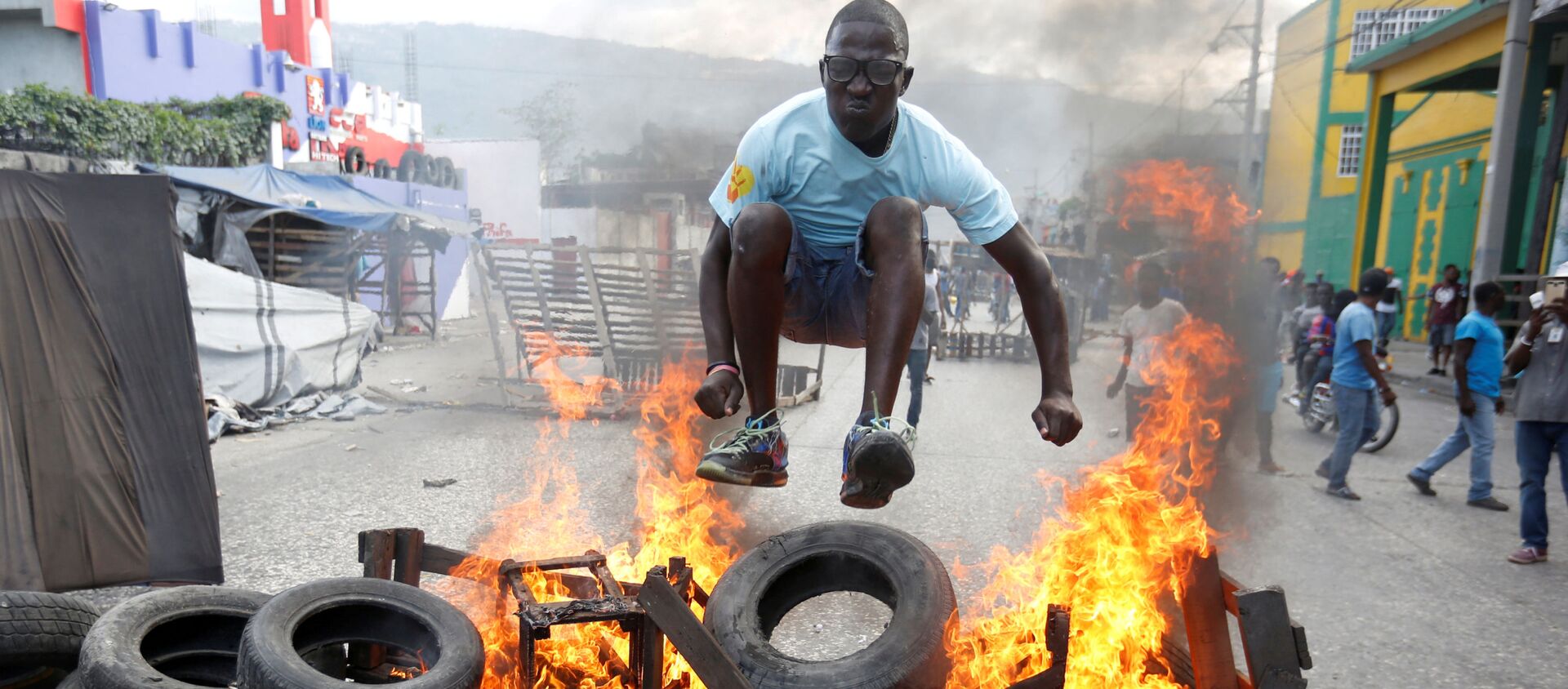 Протестующий перепрыгивает через горящую баррикаду во время акции протеста против правительства на улицах Порт-о-Пренса, Гаити, 10 февраля 2019 года. - Sputnik Абхазия, 1920, 17.02.2019