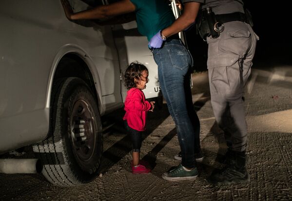 Плачущая девочка на границе Джона Мура изображает маленькую девочку из Гондураса, чью мать обыскивают американские пограничники в Техасе - Sputnik Абхазия