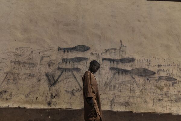 Снимок Марко Гуалаззини Мальчик из Алмаджири изображает ребенка в городе Бол в Чаде у стены, разрисованной изображениями гранатометов. В этом районе активна группировка Боко Харам, пополняющая здесь ряды своих бойцов - Sputnik Абхазия