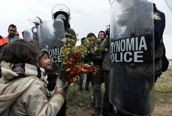 Дети дарят цветы сотрудникам греческой полиции после столкновений у лагеря беженцев в Диавате, Греция - Sputnik Абхазия