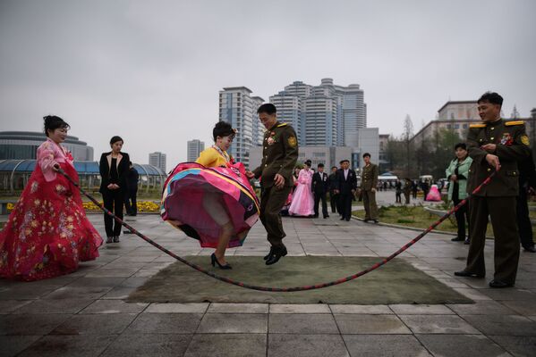 Новобрачные прыгают через скакалку во время свадебной фотосессии в Пхеньяне, Северная Корея - Sputnik Абхазия