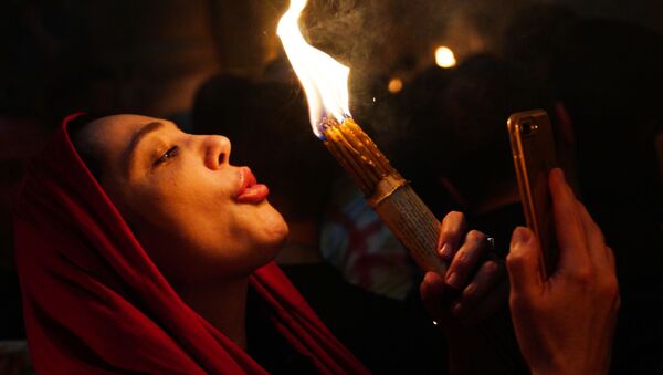 Женщина празднует схождение Благодатного огня в храме Гроба Господня - Sputnik Абхазия