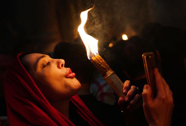 Женщина празднует схождение Благодатного огня в храме Гроба Господня - Sputnik Абхазия