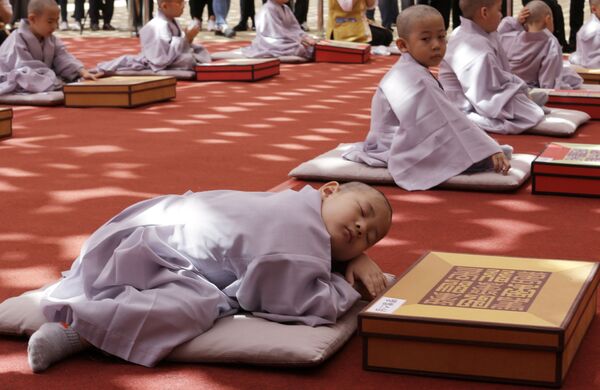 Мальчик дремлет после церемонии бритья головы и посвящения в монахи по случаю предстоящего 2563-го дня рождения Будды в храме Джогье в Сеуле, Южная Корея - Sputnik Абхазия