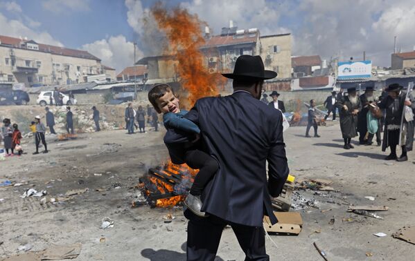 Ультраортодоксальный еврейский мужчина несет ребенка во время ритуала Биур Хамец в Иерусалиме, в канун еврейского праздника Песах (Пасха) - Sputnik Абхазия