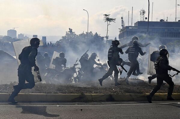 Члены Национальной гвардии Венесуэлы в облаках слезоточивого газа у военной авиабазы Ла-Карлота в Каракасе - Sputnik Абхазия