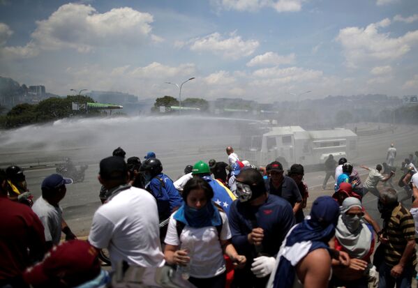 Грузовик с водяной пушкой Национальной гвардии Венесуэлы разгоняет оппозиционных демонстрантов у военной авиабазы Ла-Карлота в Каракасе - Sputnik Абхазия