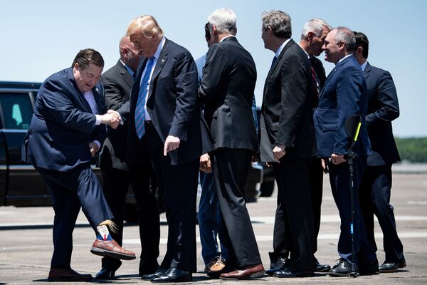 Вице-губернатор штата Луизиана Билли Нунгессер показывает президенту США Дональду Трампу носки с его изображением в аэропорте Лейк-Чарлз - Sputnik Абхазия