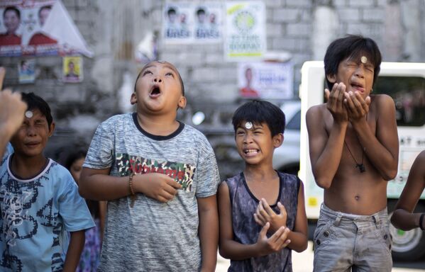 Мальчики во время конкурса по продвижению монеты со лба в рот на ежегодном празднике в честь святой Риты Кашийской в Маниле - Sputnik Абхазия