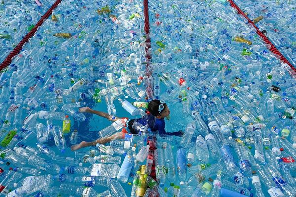 Ребенок плавает в бассейне, наполненном пластиковыми бутылками. Кампания в Бангкоке приурочена ко Всемирному дню океанов. - Sputnik Абхазия
