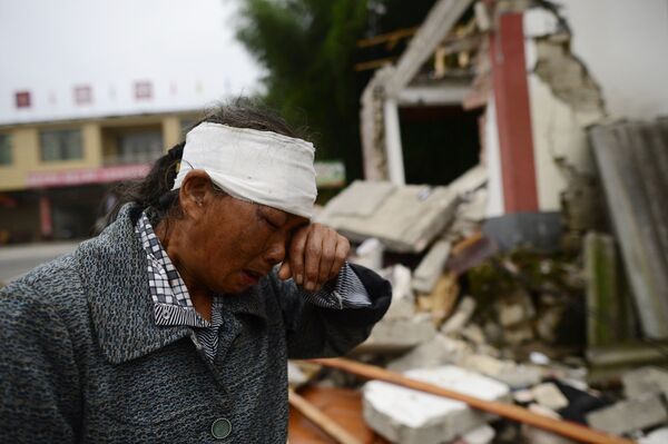 Раненая женщина плачет среди развалин домов после сильного землетрясения в городе Yibin китайской провинции Сычуань - Sputnik Абхазия